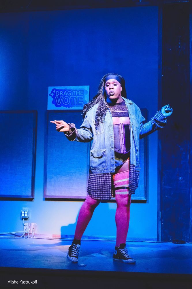 Jae Bea in a long Jean jacket, thigh high pink socks, purple corset, and long braids. Footwear, chucks 