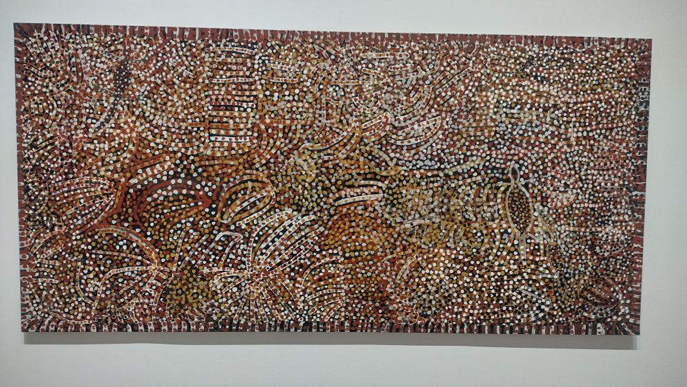 A large colourful painting with lines and shapes (there are lizards, amongst other things) and hundreds of varied dots.