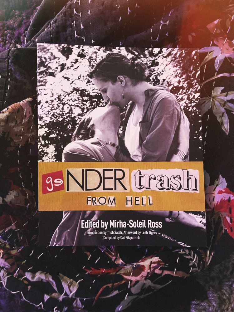 a copy of “geNDER trash FROM HELL” on a bed