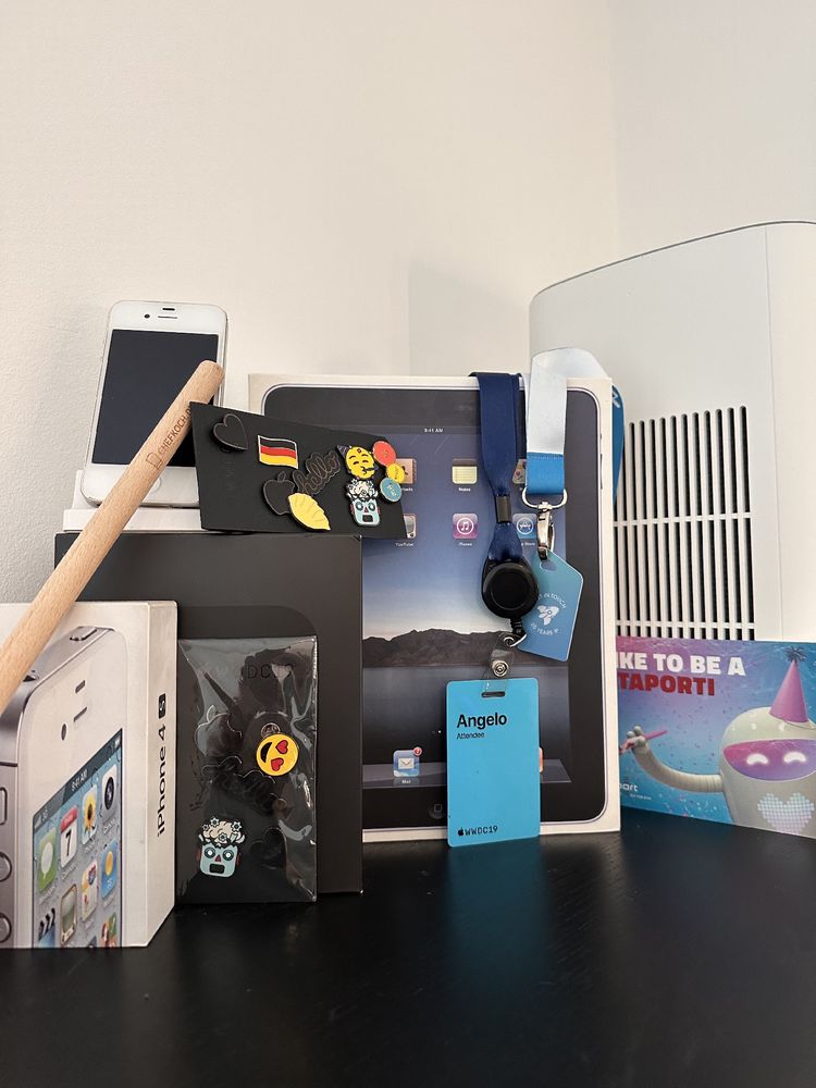 A pile of old Apple boxes like the first iPad and the iPhone 4. In addition you can find my one and only WWDC'19 attendance card, my dub dub pins and special pins (night of dimsum and subwords) also souveniers of former business partners like a Chefkoch cooking spoon.