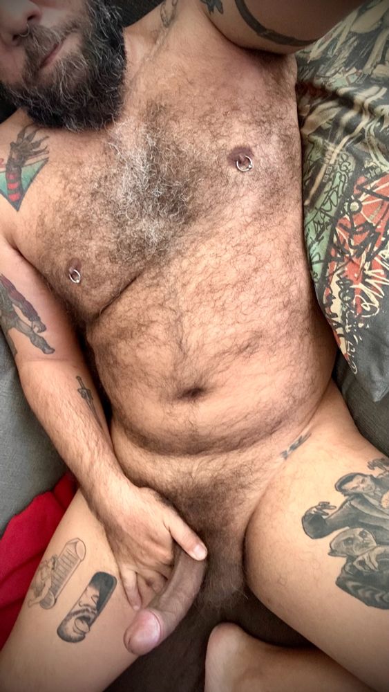 Laying naked on the sofa, showing my furry body, beard, tattoos and boner. 
