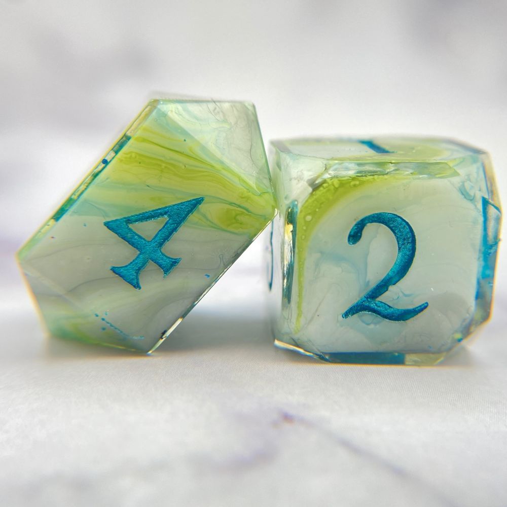 A D4 and D6 that have a white base, with swirls of lime green and teal blue, inked in a metallic teal. 