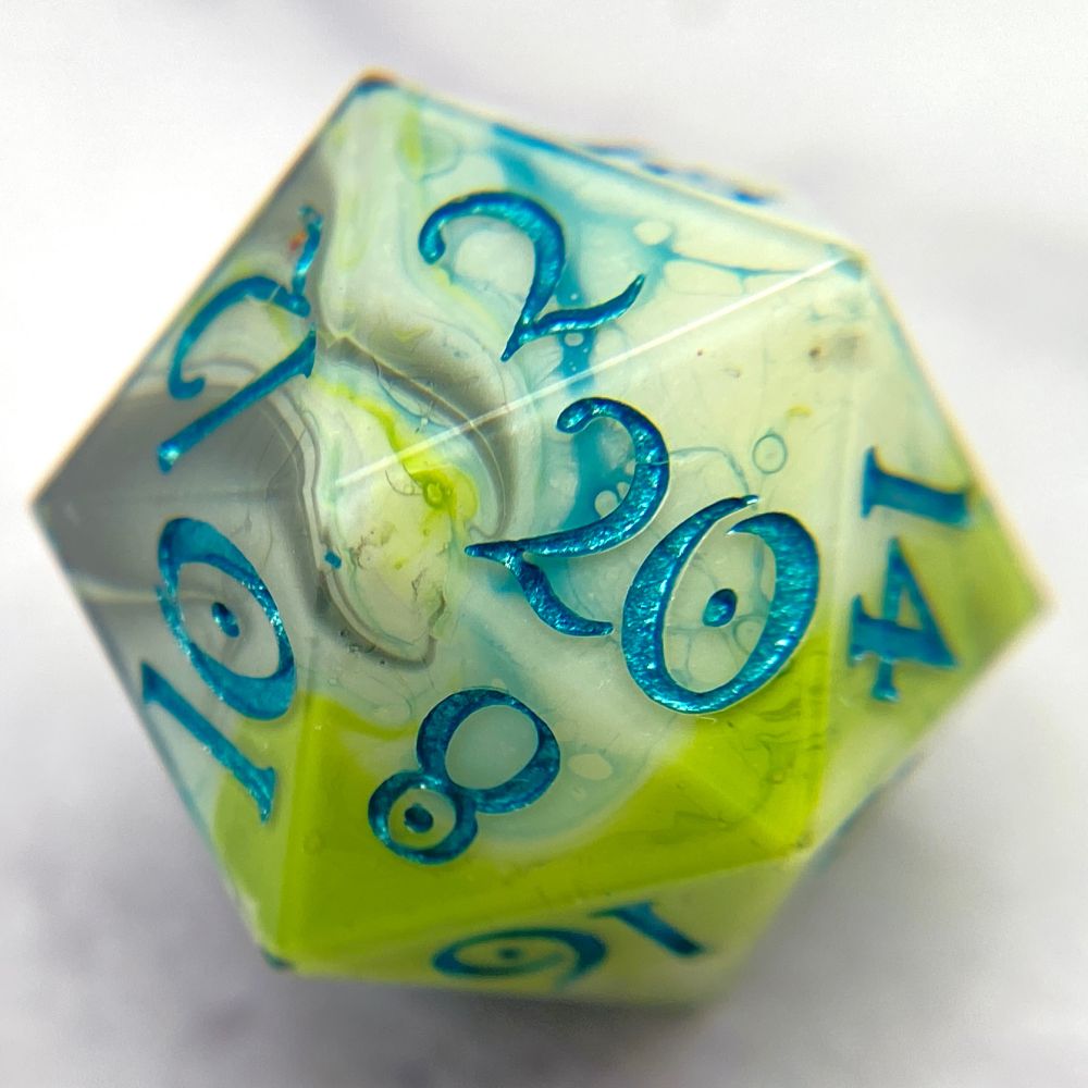 A d20 that has a white base, with swirls of black, lime green, and teal blue, inked in a metallic teal. 