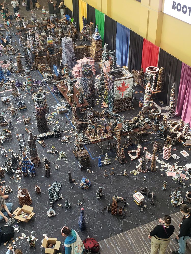An image of a section of the Indianapolis Convention Center where people are building very large structures made out of playing cards from various trading card games (such as Magic the Gathering).