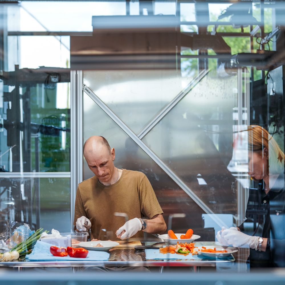 Dr. Dennis Krüger bereitet in der Testküche auf einem selbst entwickelten Biomassekocher das Mittagessen für seine Kolleg:innen vor.