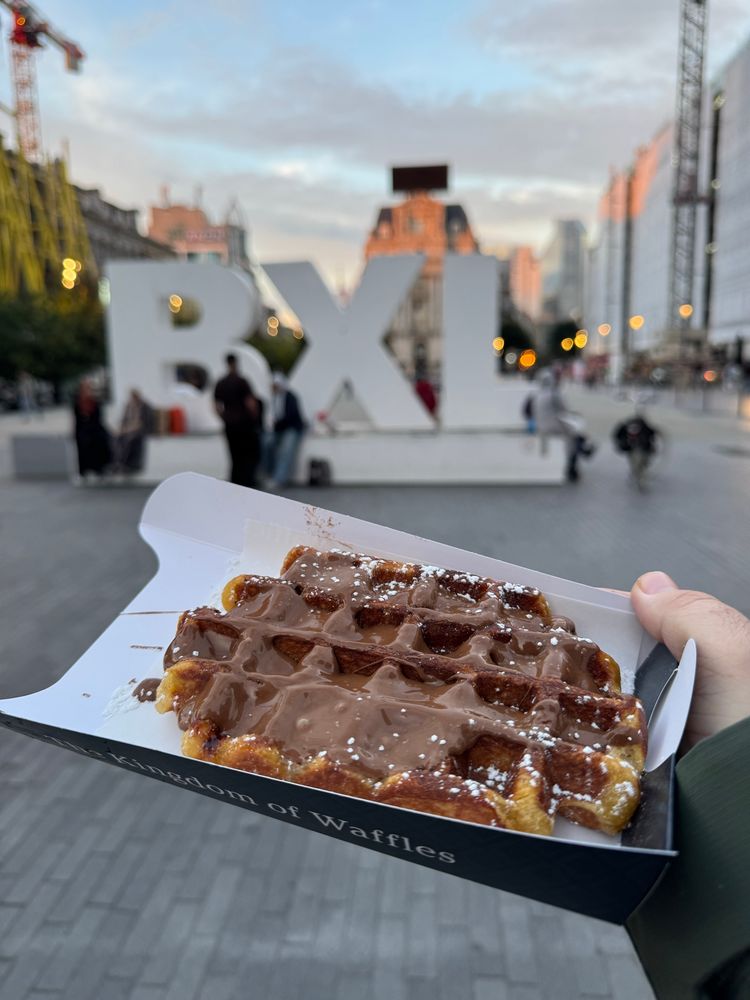 A waffle with chocolate in front of the BXL letters in a central street of Brussels.