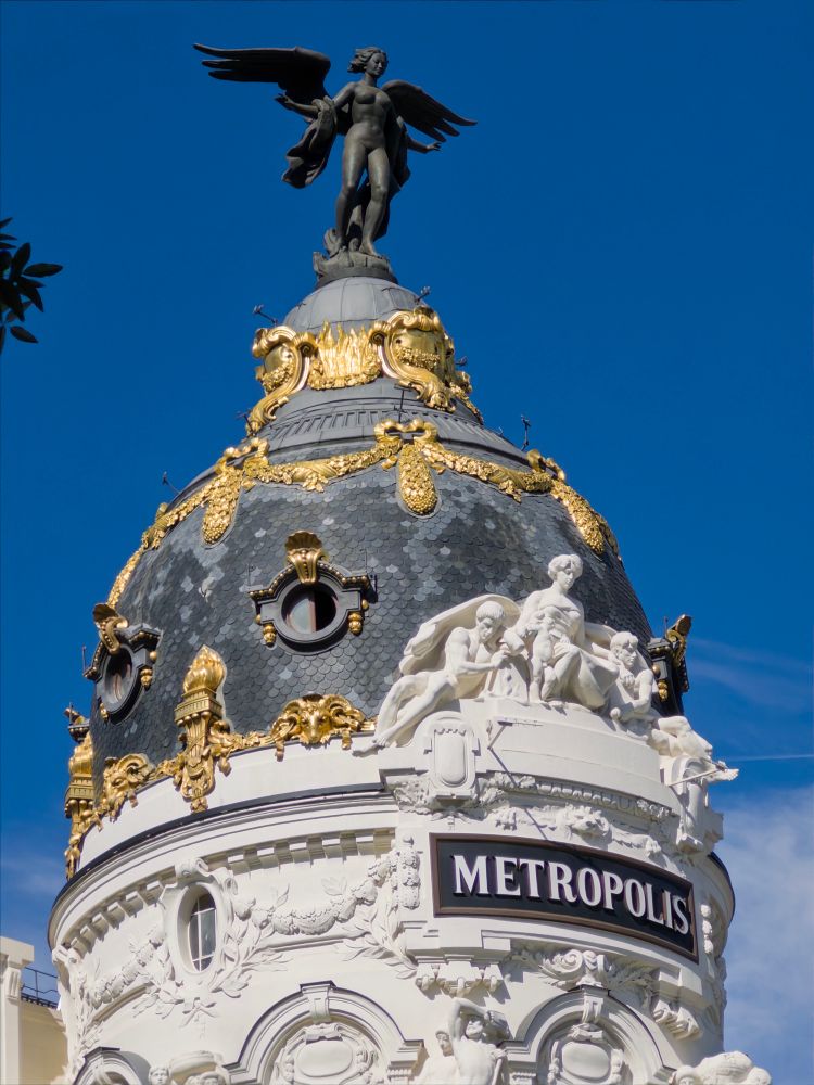 Cúpula del edificio Metripolis en Madrid. Art deco? Piedra blanca decorada con cúpula negra y dorada que culmina con la estatua de un ángel. 