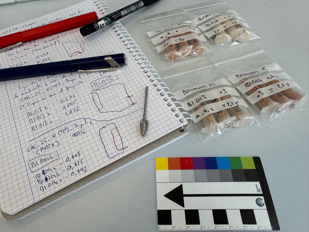 En primer plano una escala con norte y ajuste de color del proyecto Polluted Past. Encima, a su derecha, las cuatro bolsas con muestras de cerámica en polvo en sus respectivas bolsas. A la izquierda, el cuaderno con las notas… sobre él, dos plumas y la fresa de tungsteno que usé para sacar las muestras.