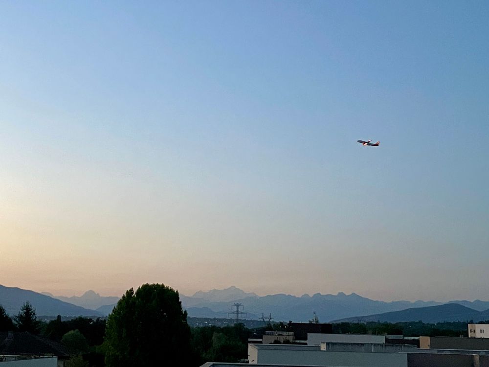 airplane over buildings and mountains 