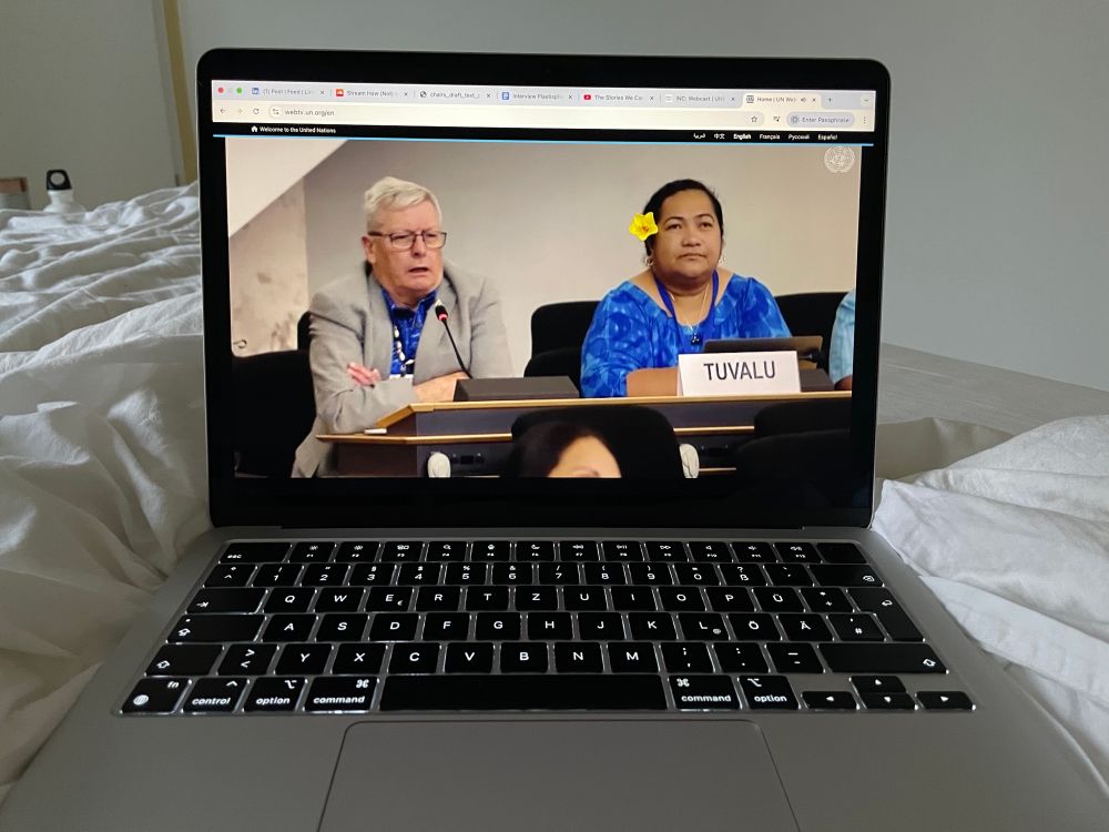 The Tuvalu delegates on the screen of a laptop on white sheets.