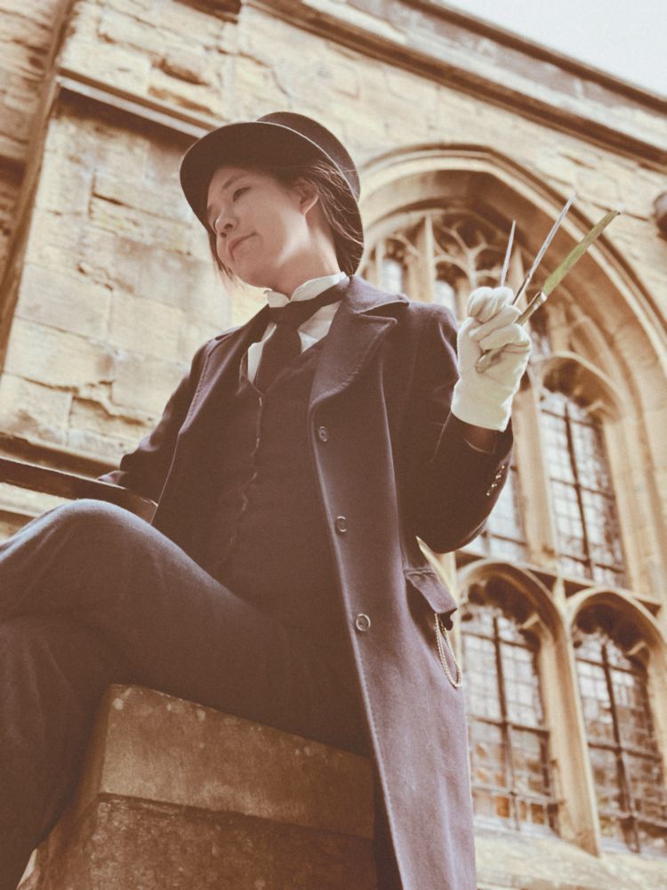 Human in a suit wielding butter knives in front of a church window