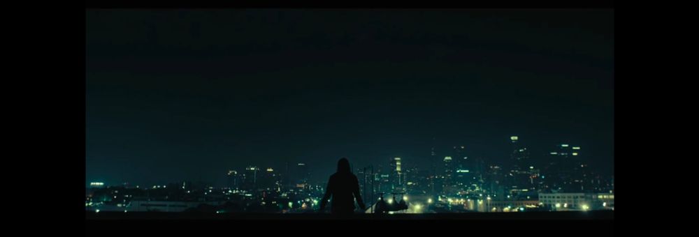 City scape shot at night with silhouette of a woman on the edge of a rooftop