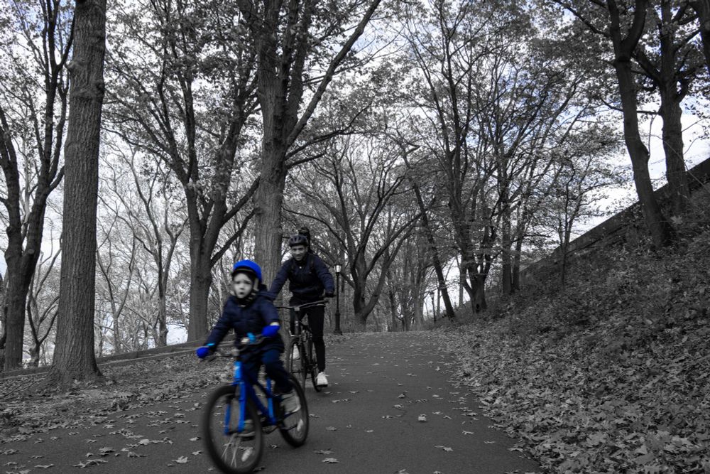 Same father son but all colors drained except the child's helmet and bike
