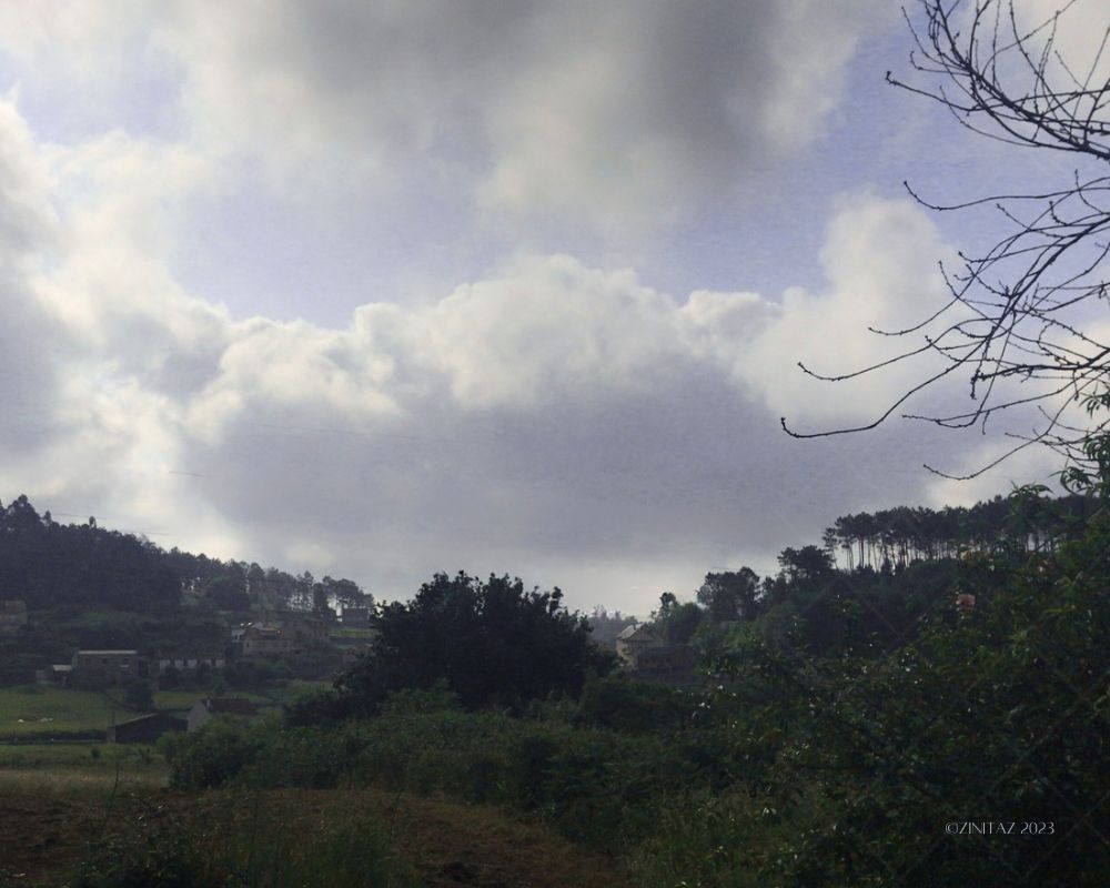 A silver glow edges the clouds above the quiet morning hills.