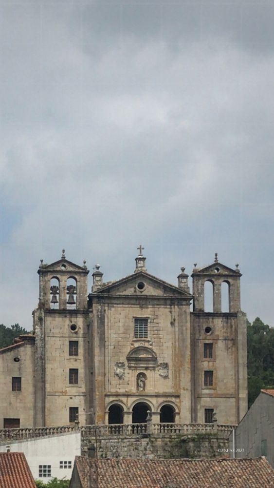 Three church towers rise quietly above the rooftops, set against a soft grey sky.