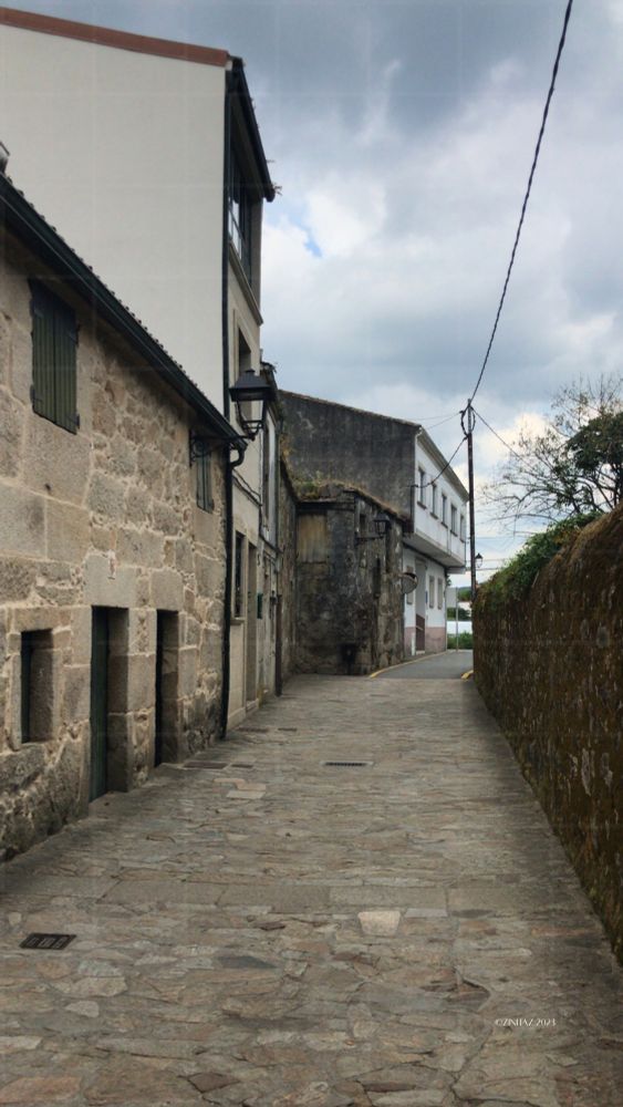 Narrow stone path curves ahead between walls and houses - step by step, stone by stone.