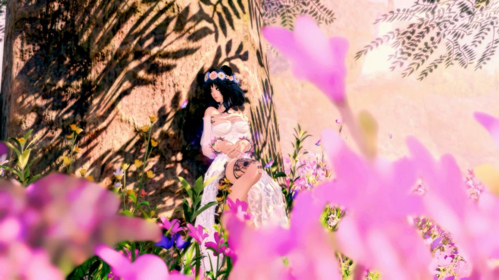 Nova leans up against a tree surrounded by pink flowers