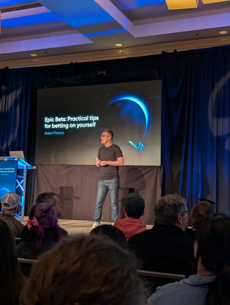 Aaron Francis on stage at Epic Web Conf with the title of his talk "Epic Bets: Practical tips for betting on yourself" on the screen in the background 
