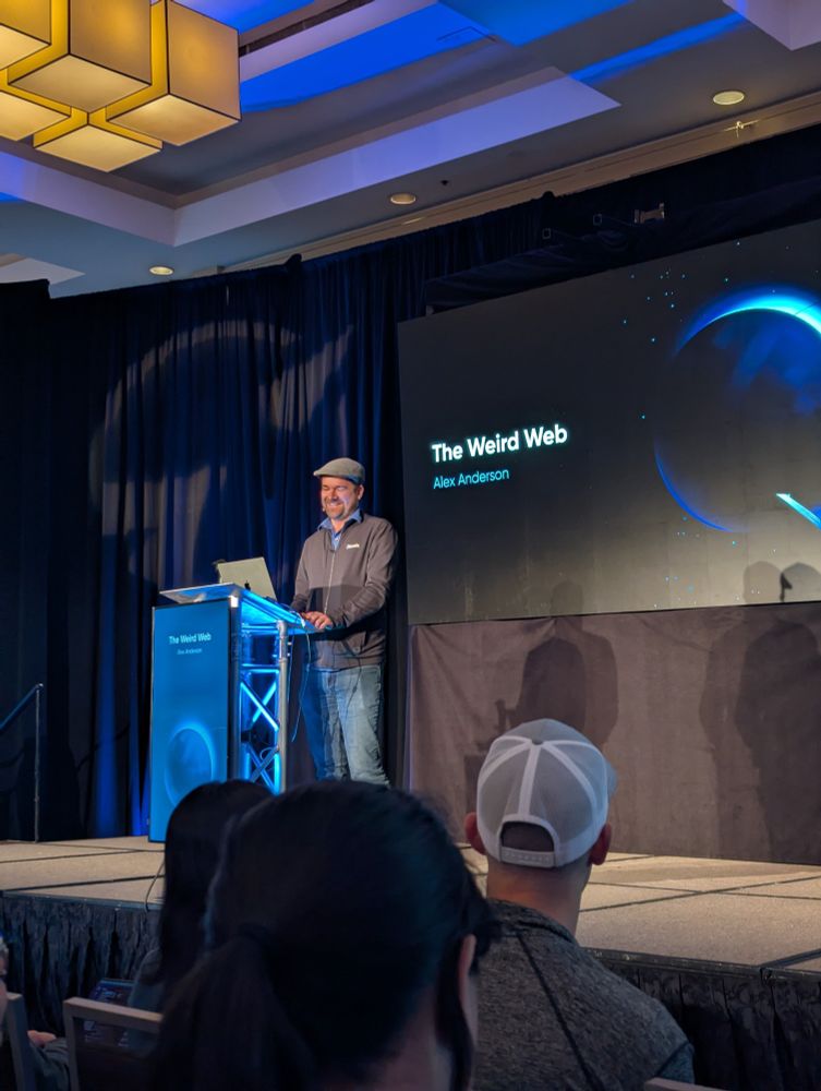 Alex Anderson on stage at Epic Web Conf with the title of his talk "The Weird Web" on the screen in the background 