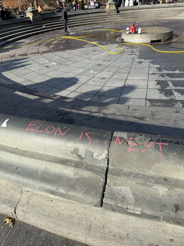 side of empty fountain with “elon is next” written on concrete