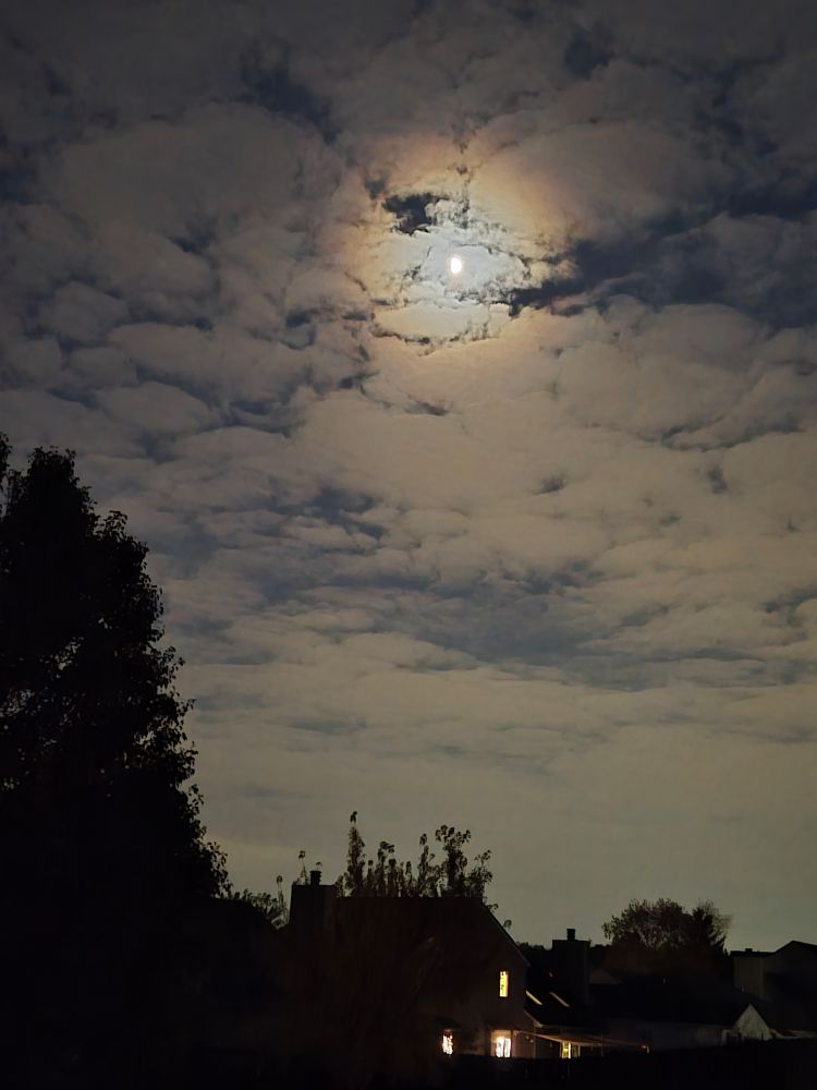 Spooky moon concealed mysteriously behind the clouds.