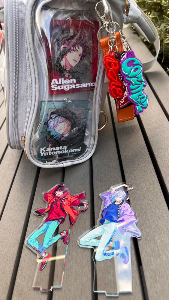 バッグの透明ポケットにアレンと珂波汰の6周年アクリルキーホルダーが入っている写真。そのバッグの手前にはDopeBoxのアレンと珂波汰のアクスタが並んでいる。