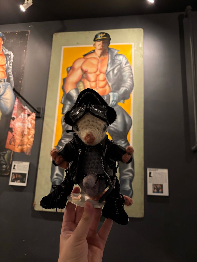 Possum held up in front of a large painting of a man in leather