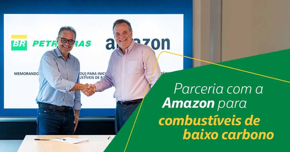 A imagem mostra o Diretor de Logística da Amazon Brasil, Ricardo Pagani, e o diretor de Logística, Comercialização e Mercados da Petrobras, Claudio Schlossers apertando as mãos em um ambiente de escritório. Ao fundo, há uma tela com os logotipos da Petrobras e da Amazon. Abaixo, um texto que diz: "Parceria com a Amazon para combustíveis de baixo carbono".
 