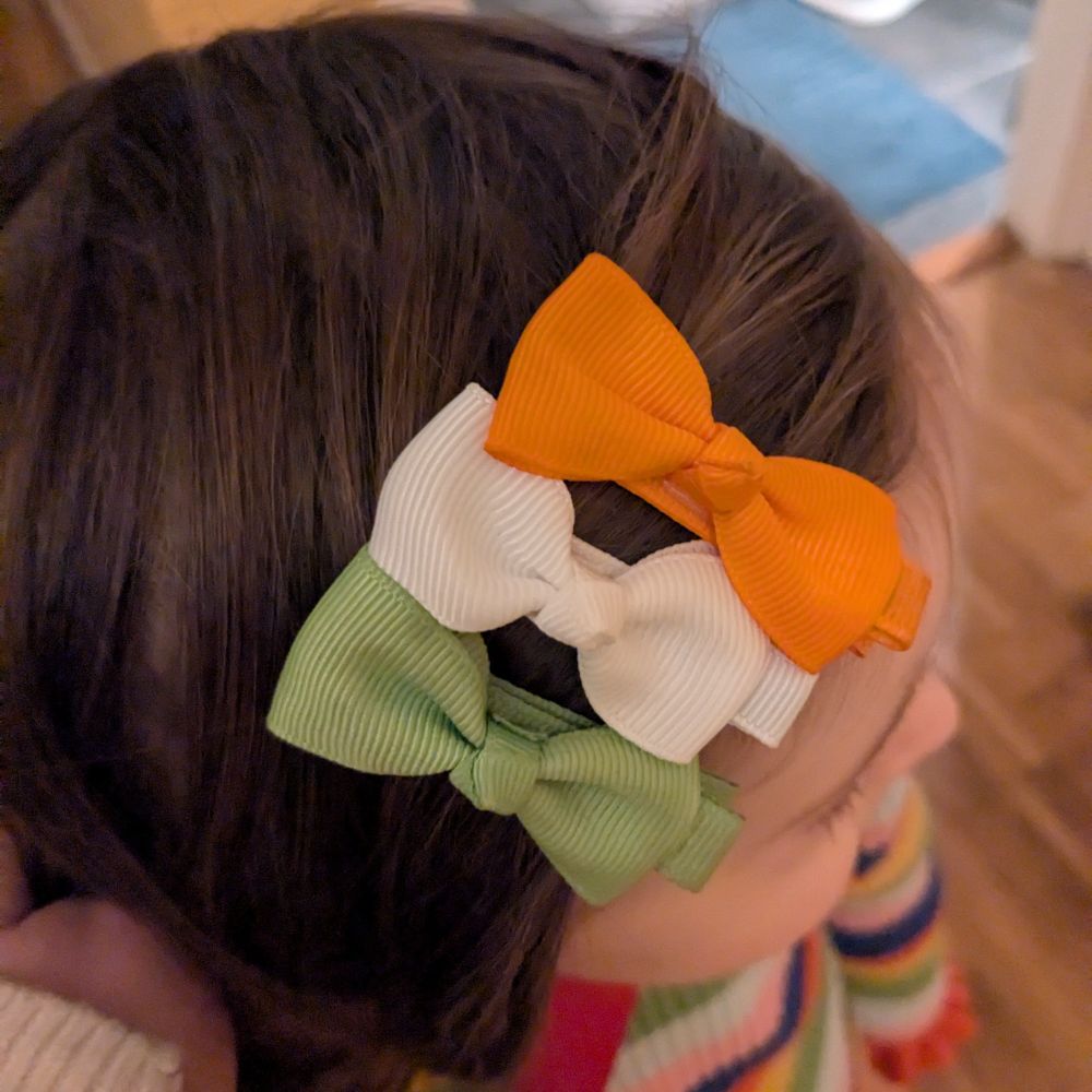 my daughter wearing three hair bows in green, white and gold to resemble the Irish flag