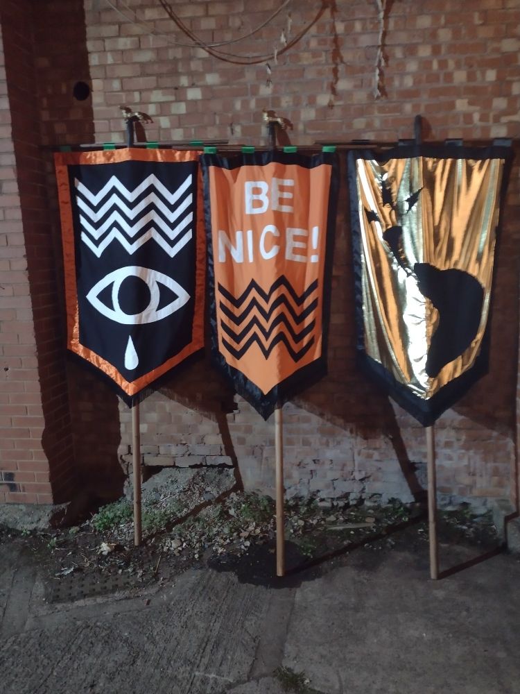 Pennants propped against a wall. One has the Supersonic logo and another reads 'be nice!'.