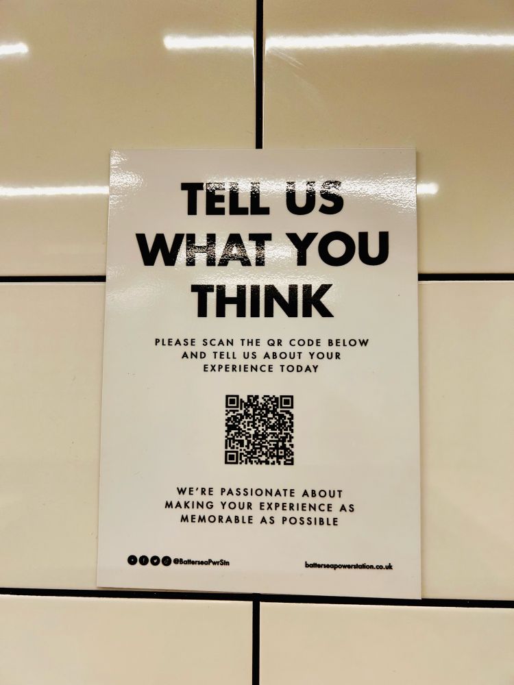 A laminated sign asking people to scan a barcode and “tell us about your experience today”.