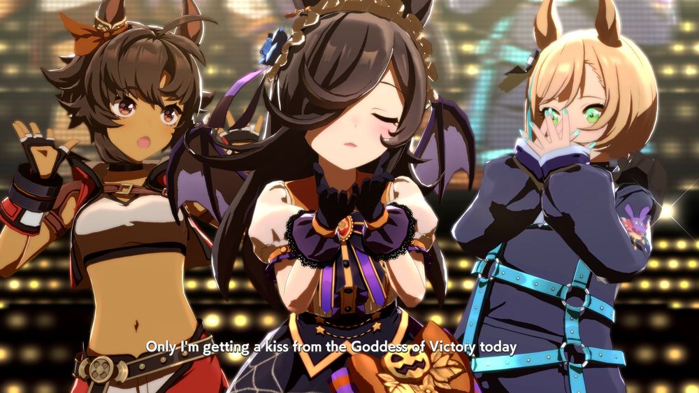 Halloween Rice Shower dancing in the center of Umapyoi with Bitter Grass on the left and Little Cocon on the right. Her eyes are closed and she's blowing a kiss to the audience while singing "Only I'm getting a kiss from the Goddess of Victory today." The other two girls are miming surprise.