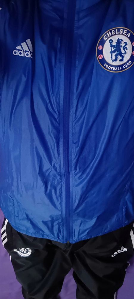 Lad laying down wearing Chelsea rain pants and a Chelsea anthem jacket. 