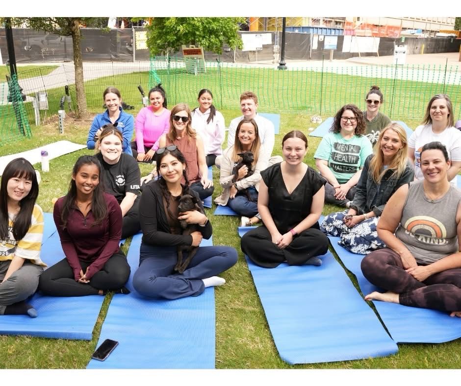 People posing on yoga mats with puppies 