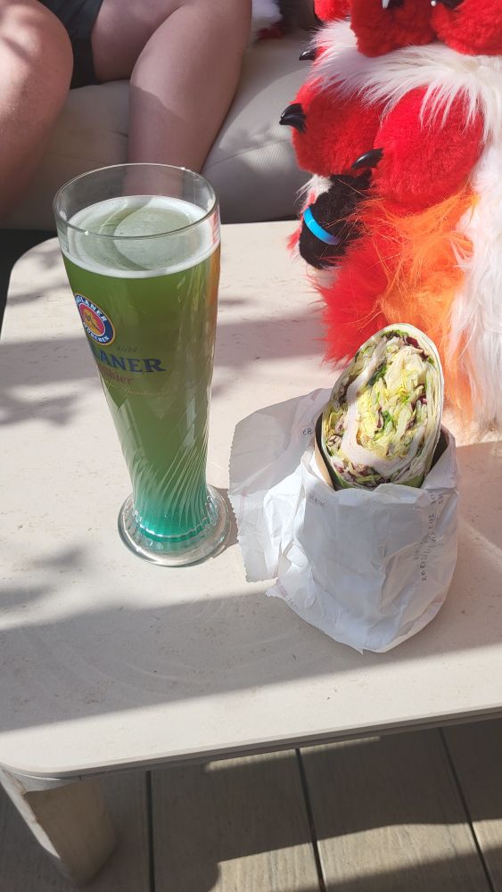 Photo of a green beer mix drink and a wrap on a table 