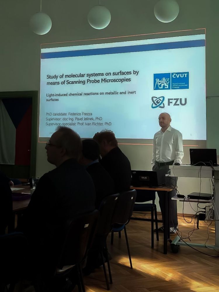 Dr. Federico Frezza presenting his PhD defence with powerpoint presentation in the background.