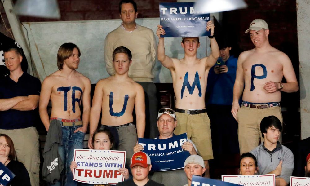 A picture of four bare-chested fascists who have the letters TR-U-M-P painted onto their chests
