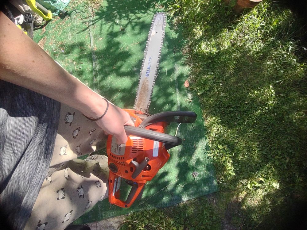 my hand holding onto my freshly-sharpened Husqvarna 120 Mk II chainsaw! also i'm wearing my exercising pandas pyjama pants, which i don't wear while chainsawing because i wear kevlar chaps because chainsaws are terrifyingly powerful