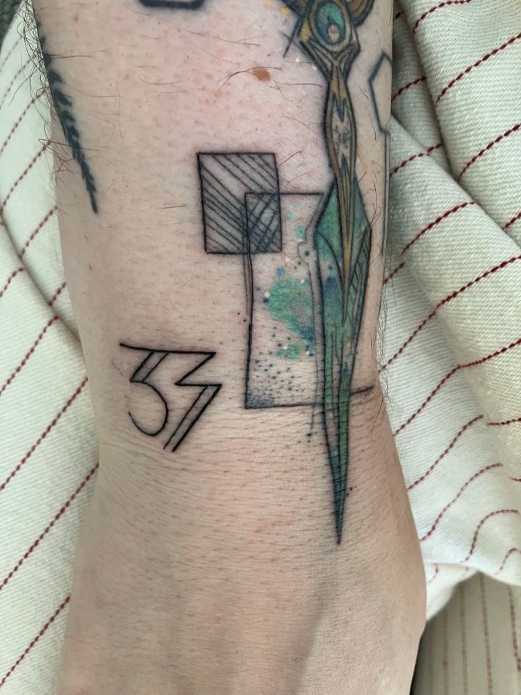 A fresh tattoo reading ‘33’ in the Expedition 33 armband font, next to an older healed tattoo of Solas’ dagger from Veilguard.
