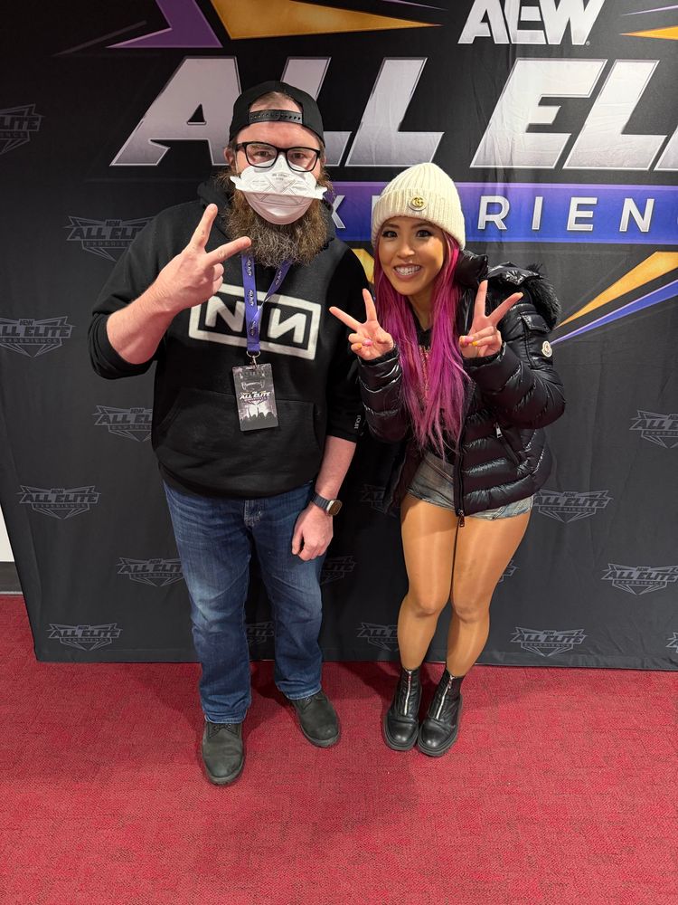 A bearded man with low self esteem and a face mask posts with Mina Shirakawa.