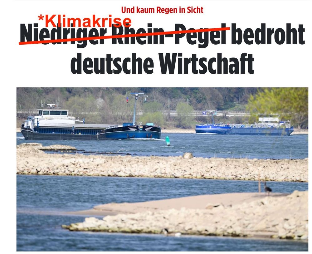 Eine bearbeitete Nachrichtenschlagzeile mit einem Bild von Schiffen auf einem flachen Fluss. Die ursprüngliche Überschrift lautete „Niedriger Rhein-Pegel bedroht deutsche Wirtschaft“, wobei „Niedriger Rhein-Pegel“ durchgestrichen und durch „Klimakrise“ ersetzt wurde. Darüber steht in kleiner roter Schrift: „Und kaum Regen in Sicht“. Im Hintergrund sieht man einen niedrigen Wasserstand mit Sandbänken, die aus dem Fluss ragen.