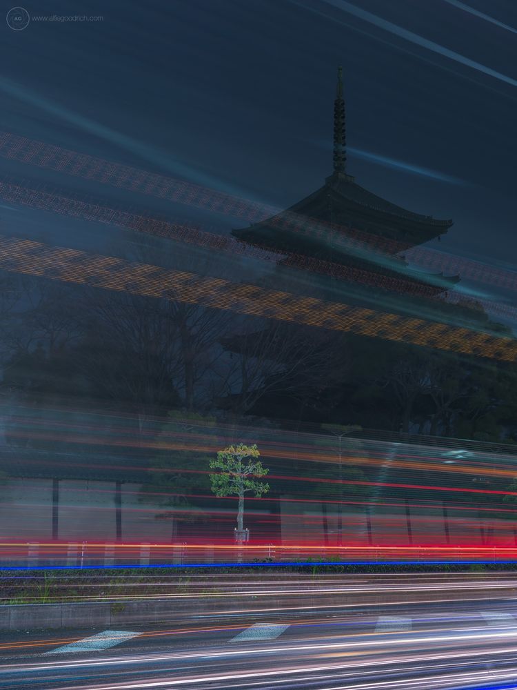 A long exposure photo of the pagoda at Tōji temple. Exposure was about four and half minutes. Shot taken from the main road so there are many light trails, from cars, buses and passing trucks. Spread vertically throughout the frame. The five-storey pagoda is in silhouette. One single tree that is by the side of the road is lit up by all the headlights of the passing vehicles. Image was originally shot for a feature in the Canadian Automobile Association magazine, back in 2017.