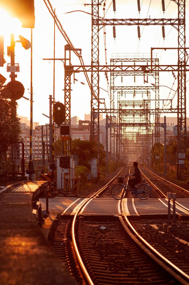 A bicycle crosses the level crossing by Kawasaki Daishi station. Photographed this back in 2009. At the end of a day exploring the nearby temples. Two railways tracks of the Daishi branch of the Keikyu Line head away from the camera, towards Kawasaki and the sunset. 