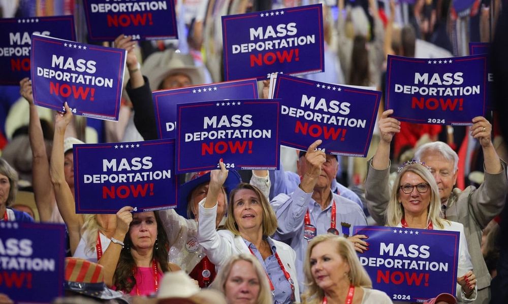 Attendees of one of Trump’s 2024 rallies holding signs mass-produced by the campaign which say “MASS DEPORTATION NOW!”