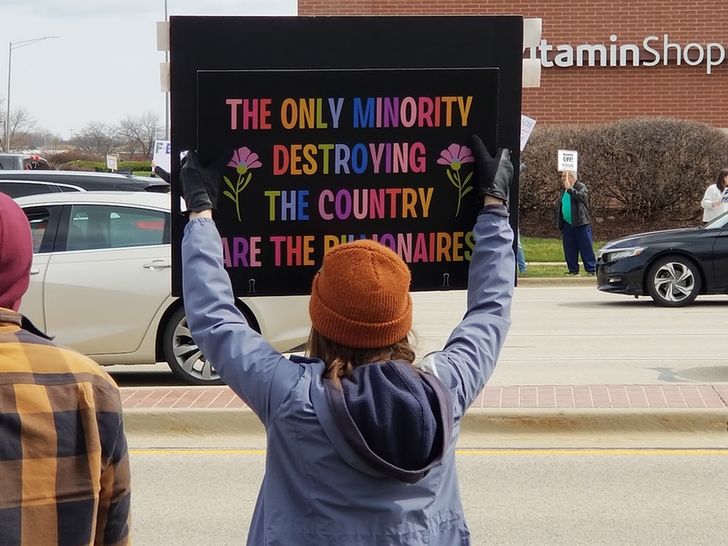 A person holding up a protest sign that says "The Only Minority Destroying the Country are the Billionaires" 