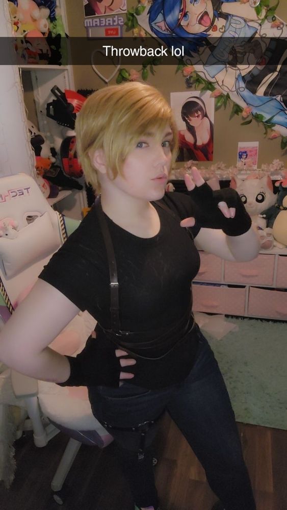 Old pic of Katie #cosplay of Leon Kennedy from Resident Evil. She has short blonde hair and is wearing a black shirt (got some wig hair on it oops) and jeans and some random belts and harness thing she found. And fingerless gloves "throwback lol"