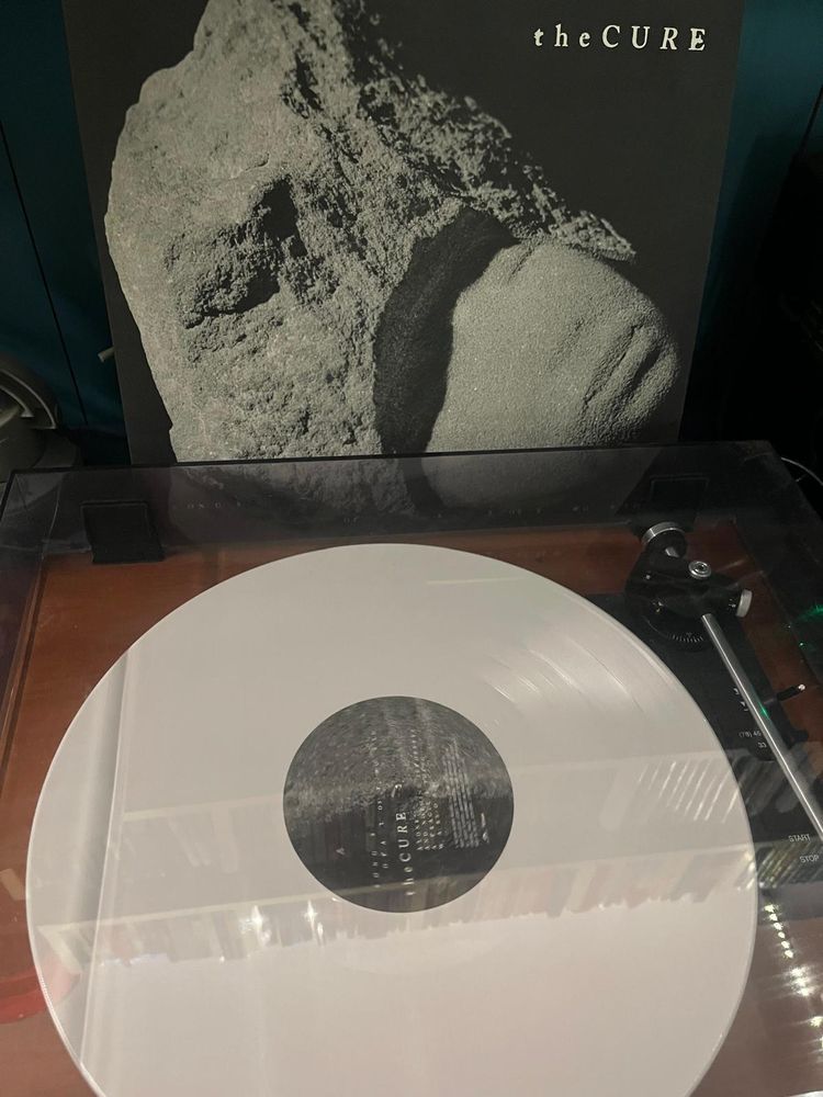 White vinyl of The Cure "Songs of a lost world" on the turntables with coverin the back ground.
Weiße Schallplatte von The Cure "Songs of a lost worgl" auf einem Plattenspieler mit dem Cover imHintergrund 