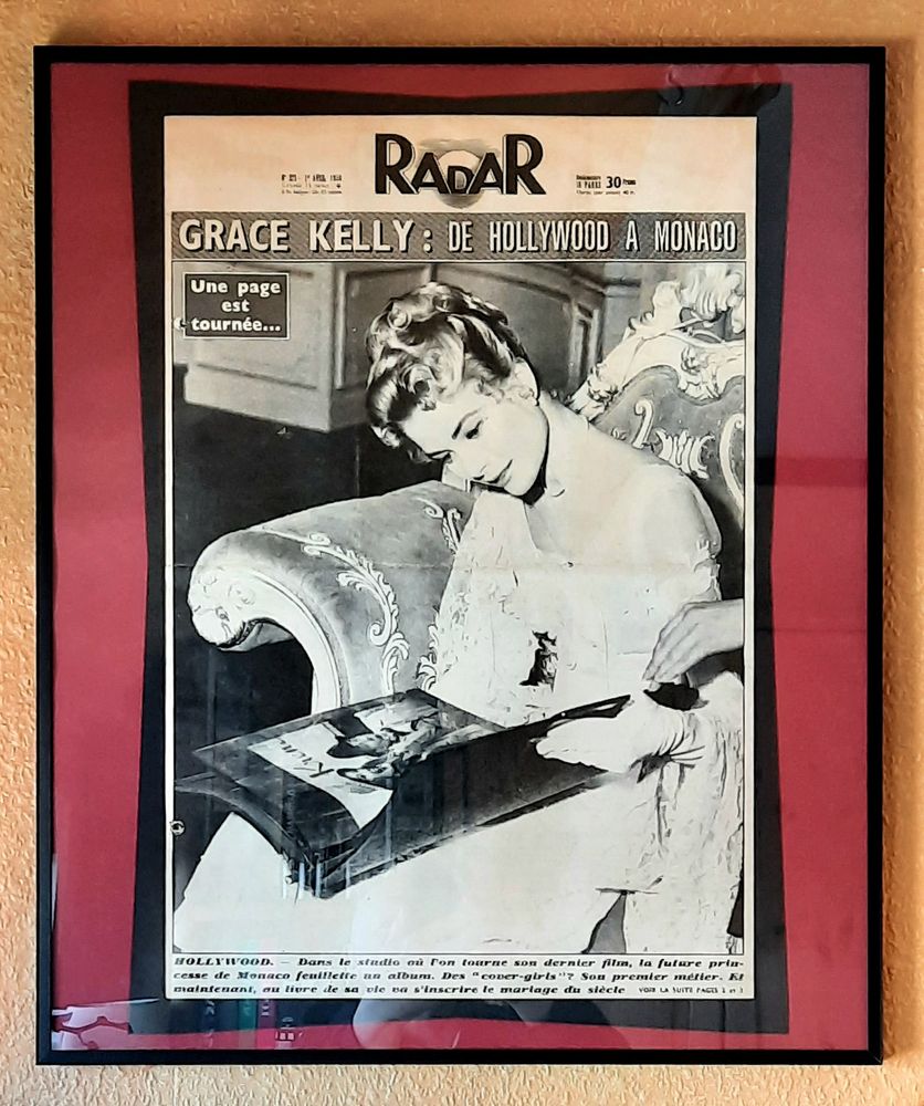 Die großformatige Zeitung wie Bildzeitung mit einem seitenfüllenden schwarzweiß-Foto von Grace Kelly auf dem Cover in einem schwarzen Glasrahmen mit rotem Passepartout.