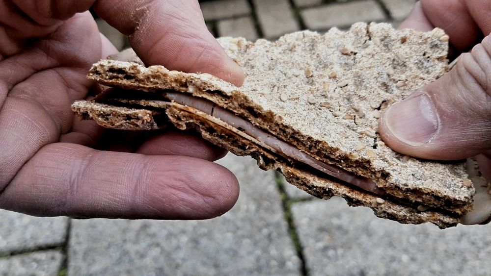 Ein Knäckebrot wird mit zwei Händen verbogen, ohne dass es bricht. Die Feuchtigkeit der Wurst hat es durchgeweicht.