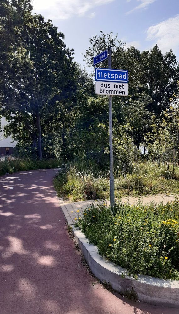 Ein Fahrradweg zweigt ab. Das niederländisch Schild am Anfang textet: Fietspad. Dus niet brommen.